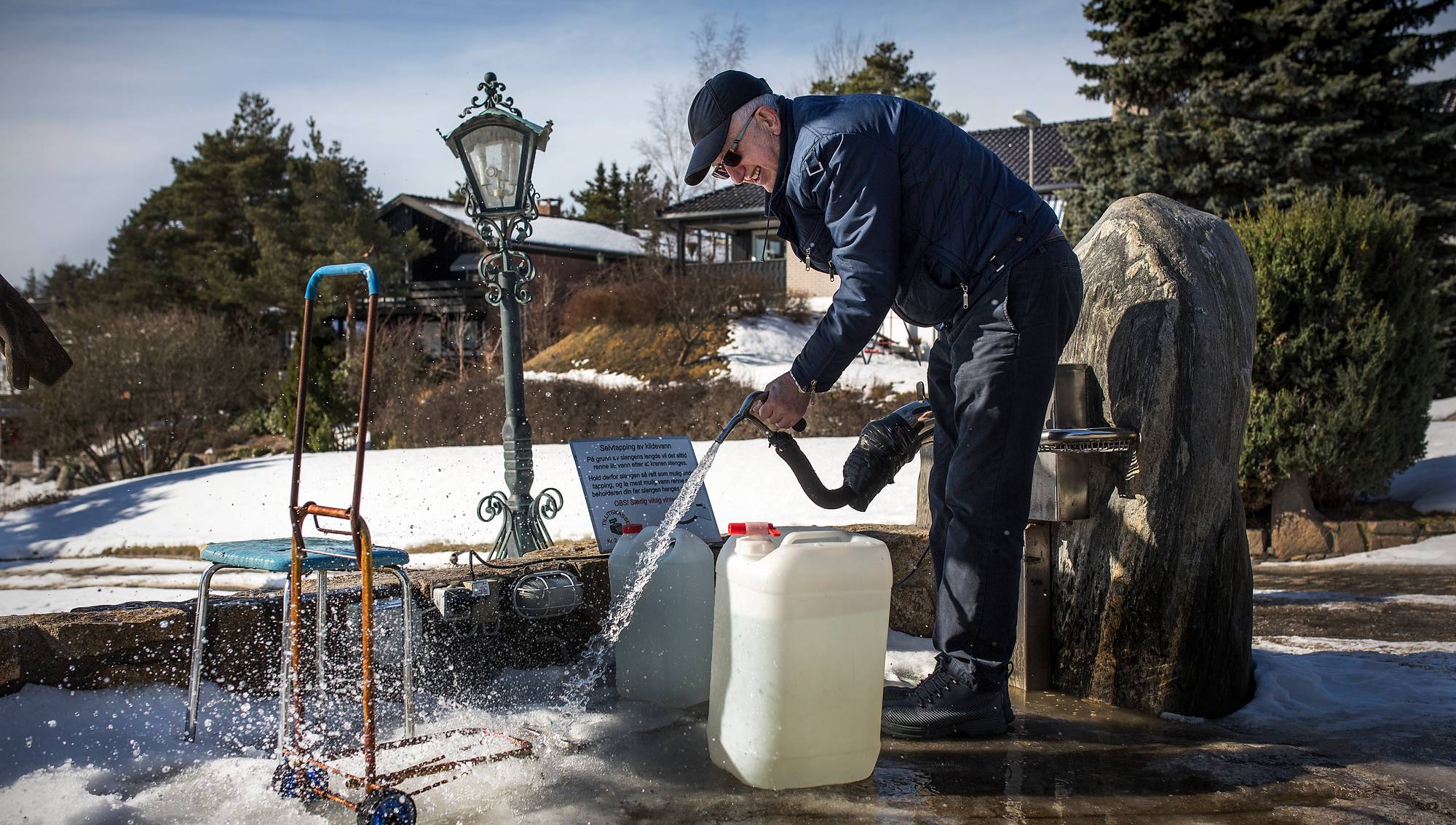 En kunde fyller vann fra Olavskilden om vinteren